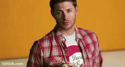 Man In Plaid Shirt Standing In Front Of Orange Wall GIF