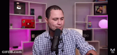Man In Plaid Shirt Talking Into Microphone GIF