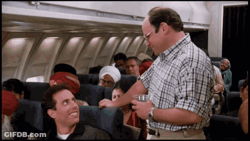 Man In Plaid Shirt Talking To Another Man On Plane GIF