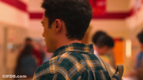 Man In Plaid Shirt Walking Hallway With Backpack GIF