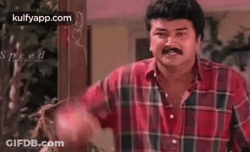 Man In Plaid Shirt With Mustache Standing In Front Of Wooden Door GIF