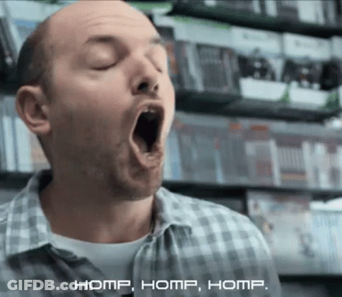 Man In Plaid Shirt Yawning By Video Game Shelf GIF