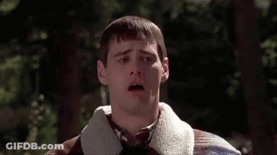 Man In Plaid Sweater And Tie Standing In Front Of Trees GIF