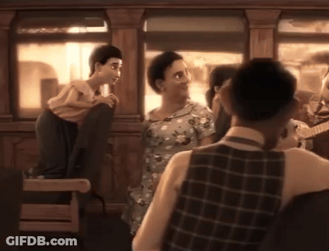 Man In Plaid Vest Next To Woman In Dress GIF