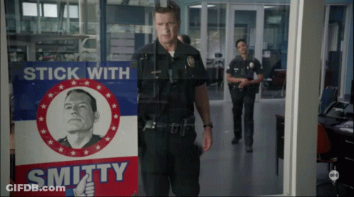 Man In Police Uniform In Front Of Stick With Smithy Sign GIF