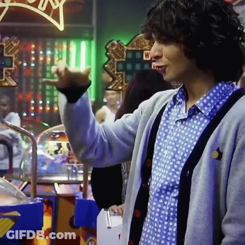 Man In Polka Dot Shirt And Gray Cardigan Standing By Lucky Star Sign GIF