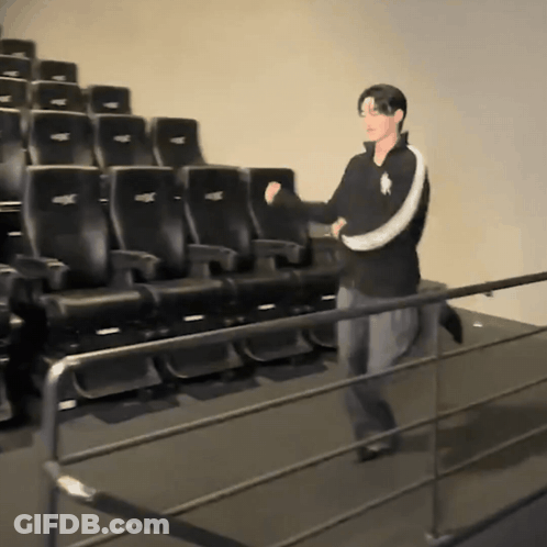 Man In Polo Shirt In Front Of Black Theater Seats GIF