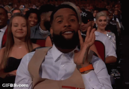 Man In Prada Vest Sitting In Crowd GIF