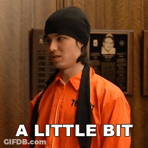 Man In Prison Uniform Says A Little Bit Wearing Black Hat GIF