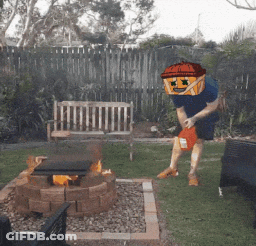 Man In Pumpkin Hat Throwing Chips Into Fire Pit GIF