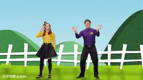 Man In Purple And Woman In Yellow Dancing In Front Of Fence GIF