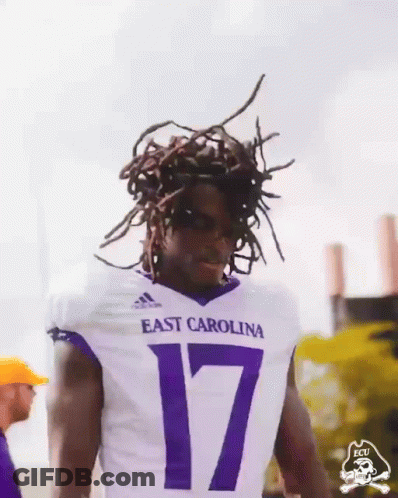Man In Purple ECU Shirt Holding Up Fist GIF
