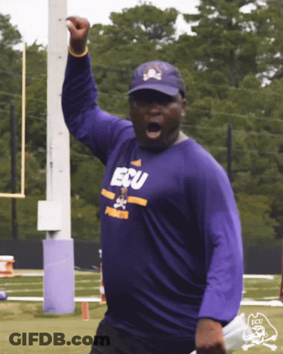 Man In Purple ECU Shirt Holding Up Fist GIF