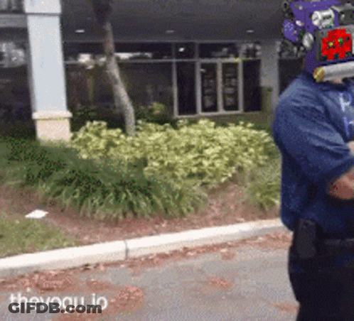 Man In Purple Helmet Walking Down Street With Thevogu.io GIF
