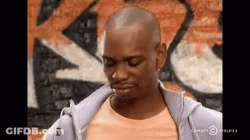 Man In Purple Hoodie In Front Of Graffiti Brick Wall GIF