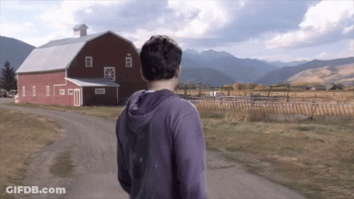 Man In Purple Hoodie Walking Past Red Barn GIF