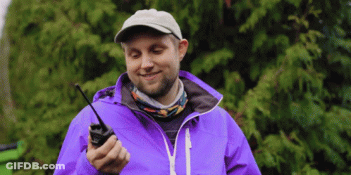 Man In Purple Jacket And Hat Holding Walkie Talkie GIF