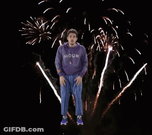 Man In Purple Moon Sweatshirt Jumping In Front Of Fireworks GIF