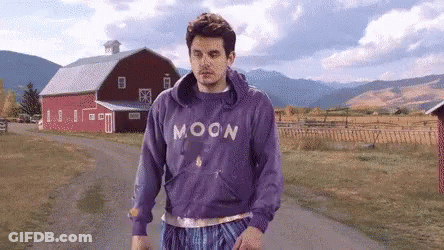 Man In Purple Moon Sweatshirt Walking Down Dirt Road GIF