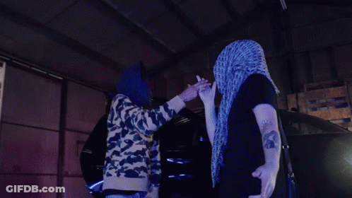 Man In Purple Scarf High-Fives Another In Dark Room GIF