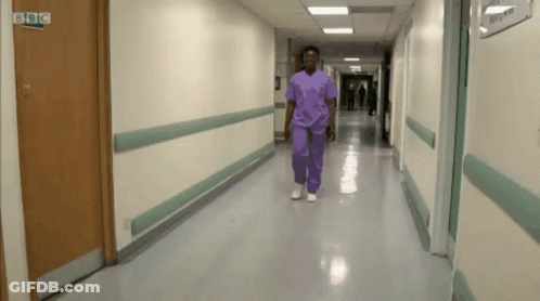 Man In Purple Scrubs Walking Past BBC Logo Door GIF
