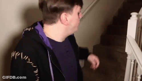 Man In Purple Shirt And Black Jacket Walking Down Stairs GIF