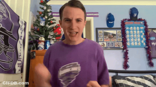 Man In Purple Shirt In Front Of Hurricanes Poster GIF