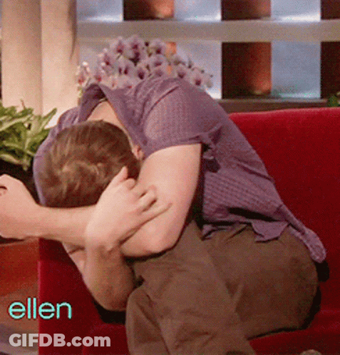 Man In Purple Shirt Sitting On Red Couch With Ellen Behind Him GIF