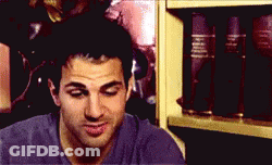 Man In Purple Shirt Smiling In Front Of Bookshelf GIF