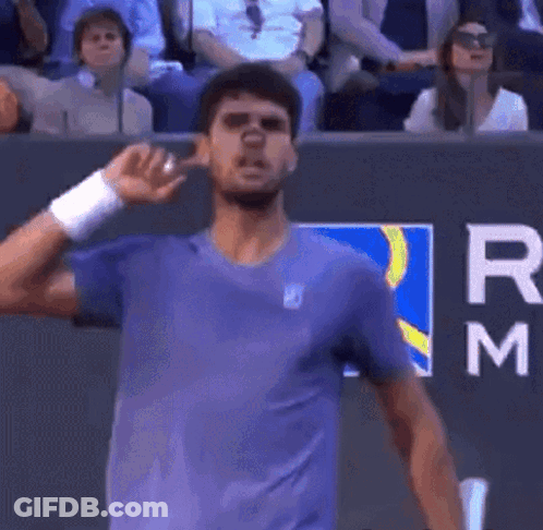 Man In Purple Shirt Standing By Letter M Wall GIF