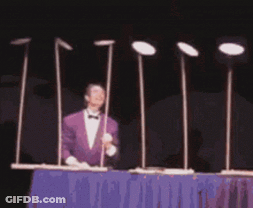 Man In Purple Suit Beside Metal Poles With Plates GIF