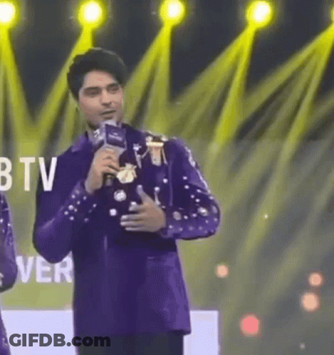 Man In Purple Suit Holding Microphone In Front Of BTV Logo GIF