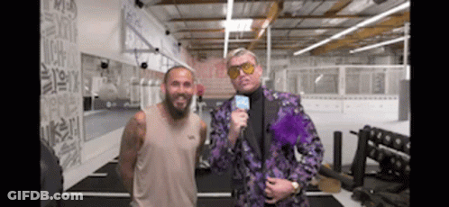 Man In Purple Suit Next To Man In Tan Tank Top In Gym GIF