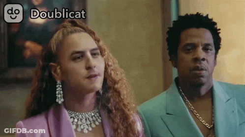 Man In Purple Suit Next To Woman With Necklace GIF