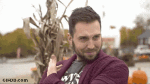 Man In Purple Sweater Standing Before Corn Stalks GIF
