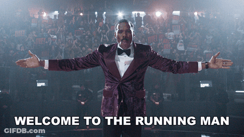 Man In Purple Tuxedo Saying Welcome To The Running Man GIF