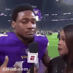 Man In Purple Vikings Uniform Talking Into Microphone Woman Looking On GIF