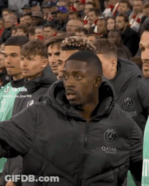 Man In Qatar Jacket Standing In Crowd GIF