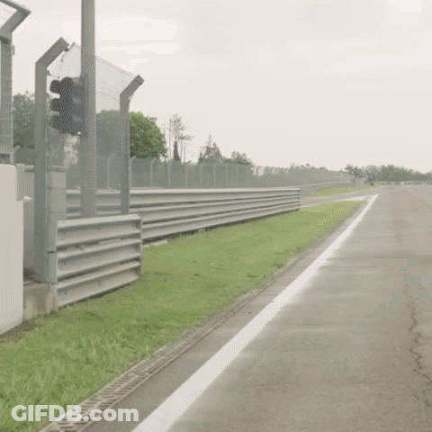 Man In Racing Suit Walking Down Race Track GIF