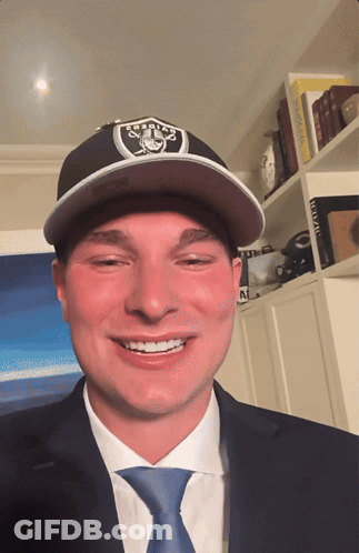 Man In Raiders Hat And Tie Smiles GIF