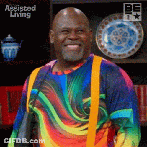 Man In Rainbow Shirt And Suspenders Smiling With Plates GIF