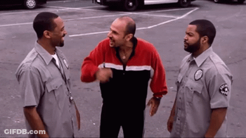 Man In Red And Black Jacket Talking To Guards GIF