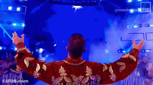 Man In Red And Gold Sweater Standing On Stage GIF