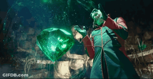 Man In Red And Green Coat Holding Large Emerald GIF
