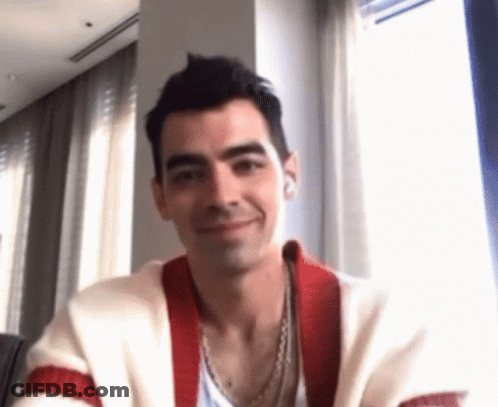Man In Red And White Sweater Smiling At Table By Window GIF