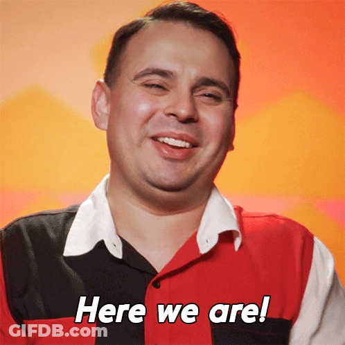 Man In Red Black And White Shirt Smiling Saying Here We Are GIF