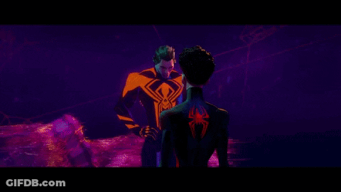 Man In Red Cape In Front Of Screen With Two People GIF