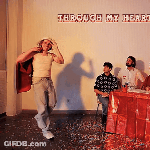 Man In Red Cape Stands Before Wall Saying Through My Heart GIF