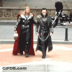 Man In Red Cape Walking Next To Man In Black Suit GIF