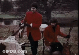 Man In Red Coat Playing Tambourine And Man On Chair Playing Guitar GIF